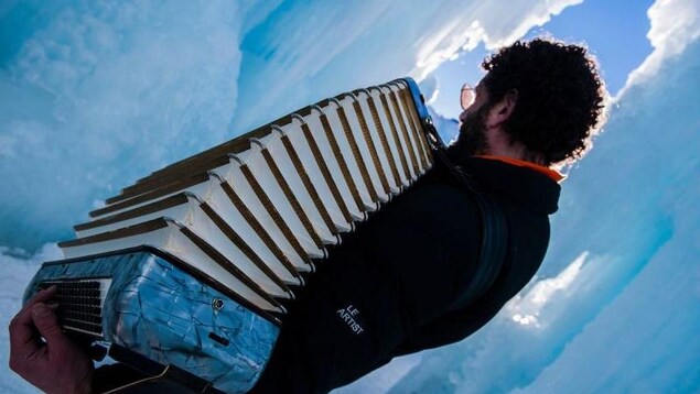 Un musicien joue de l'accordéon entouré de neige. Un musicien joue de l'accordéon entouré de neige.