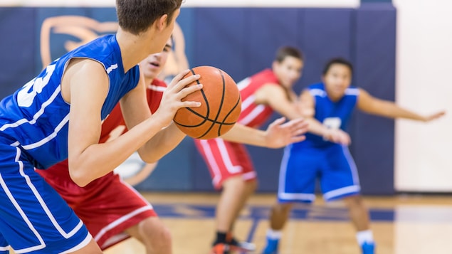 Des adolescents jouent au basketball dans un gymnase.