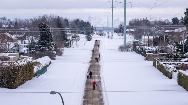 Des gens marchent sur une piste linéaire en hiver.