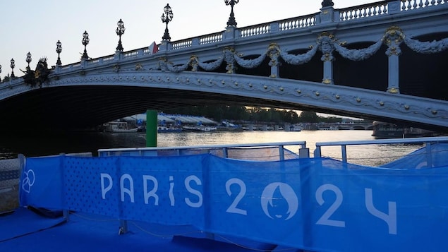 A bridge over the Seine with a large banner "Paris 2024" on a platform next to it.