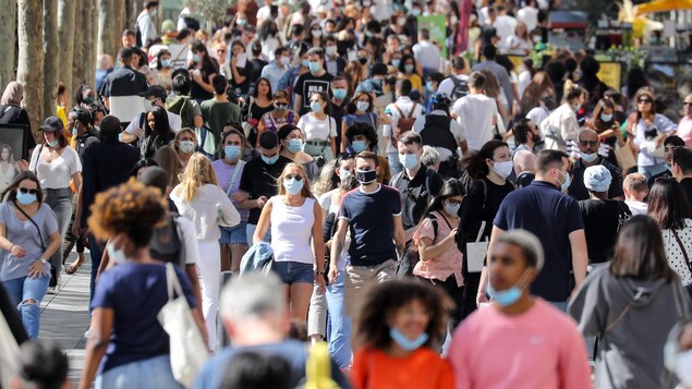 Des passants portant un masque facial marchent sur l'avenue des Champs-Élysées à Paris.