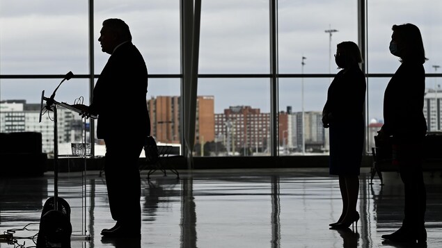 Doug Ford en contre-jour avec deux silhouettes féminines dans son dos.