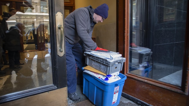 Un homme se penche sur des boîtes de documents.