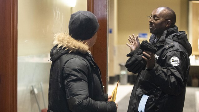 Une personne tente d'entrer dans le ministère de l'Immigration, où se trouve un gardien de sécurité.