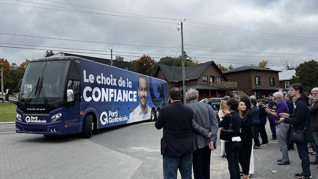 L'autobus du Parti québécois dans un stationnement à Montebello, attendu par plusieurs personnes.