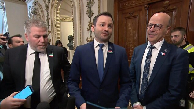 Trois hommes lors d'une mêlée de presse au Parlement.