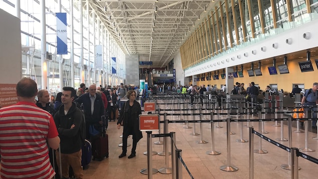 Des passagers attendent après avoir été évacués de certaines zones de l'aéroport. Des passagers attendent après avoir été évacués de certaines zones de l'aéroport.