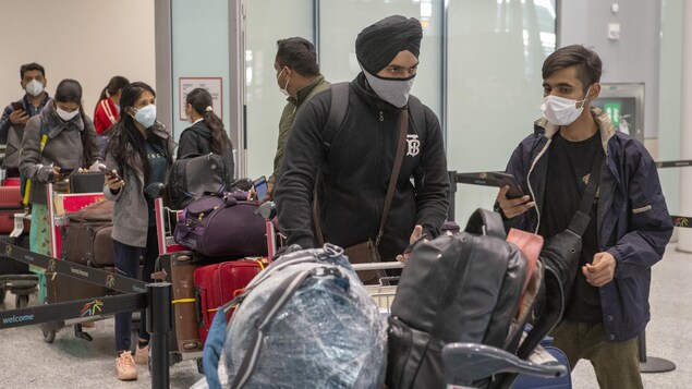 Des voyageurs attendent en file avec leurs bagages.