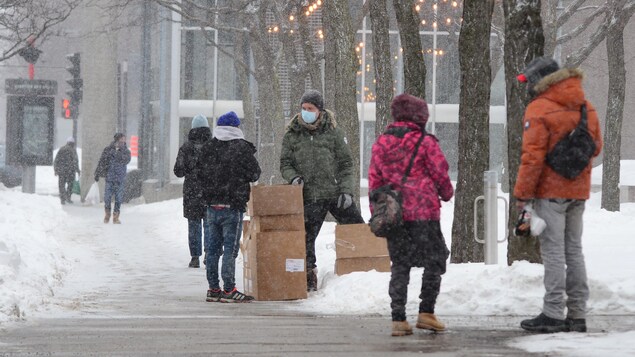 Des gens marchent dans la rue alors qu'il neige.