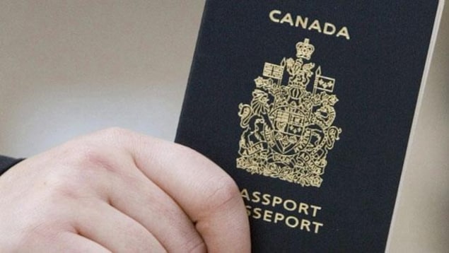 يد تمسك بجواز سفر كندي.