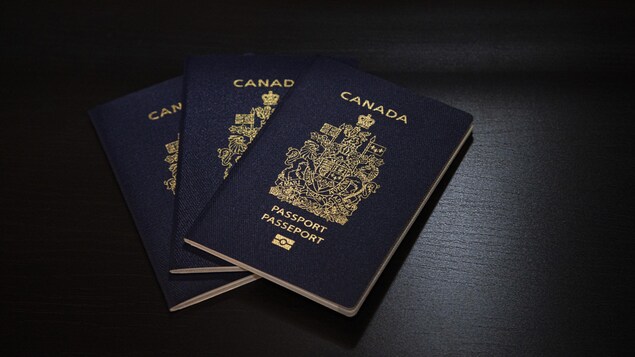 Trois passeports canadiens posés sur une table.