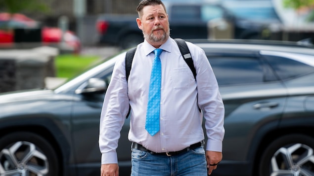 Pat King marche vers le palais de justice à Ottawa. Il est vêtu d'un jeans, d'une chemise de couleur gris pâle et d'une cravate bleue.