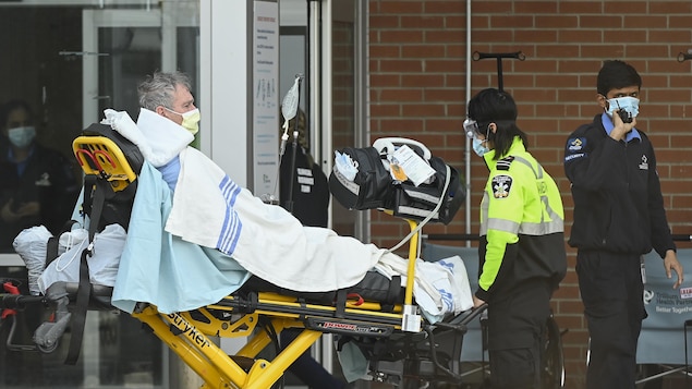 Des ambulanciers amènent un patient sur une civière à l'hôpital à Mississauga.