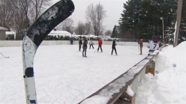 Des gens jouent au hockey sur une patinoire extérieure.