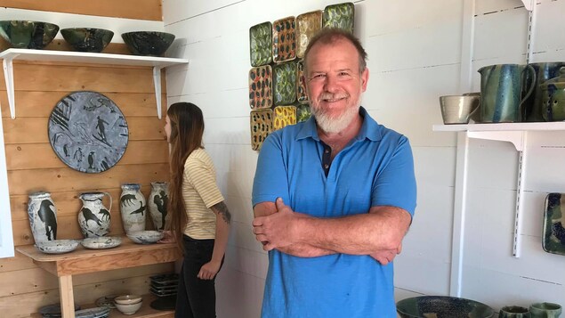 Patrick Le Blond se tient devant ses œuvres, à l'intérieur de son atelier-galerie.