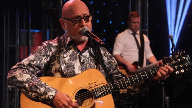 Patrick Norman chante et joue de la guitare.