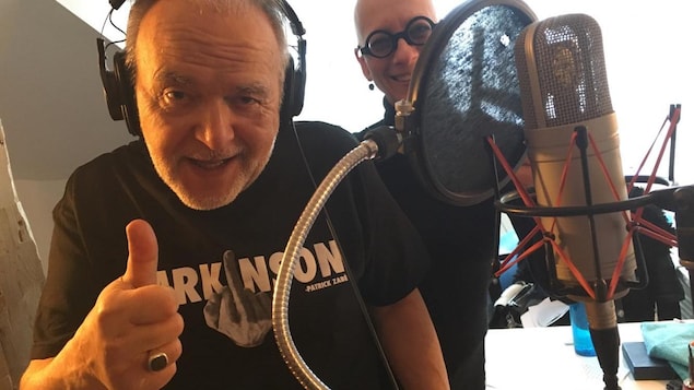 Patrick Zabé au studio The Trench de Québec lors de l'enregistrement de la pièce « Le zéro du texto ». On l'aperçoit devant un micro, heureux et légèrement voûté. Sa femme est à ses côtés.