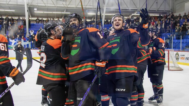 Des joueurs de hockey sur une patinoire saluent la foule.