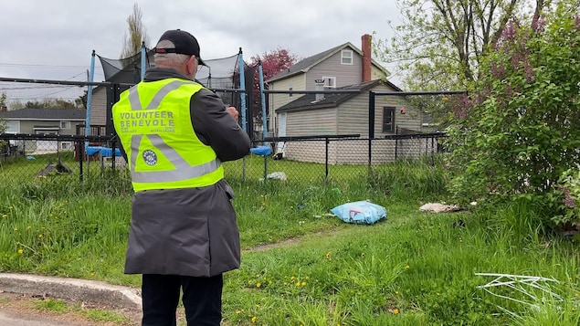 Une personne qui entre des données dans un téléphone non loin d'un amoncellement de déchets.