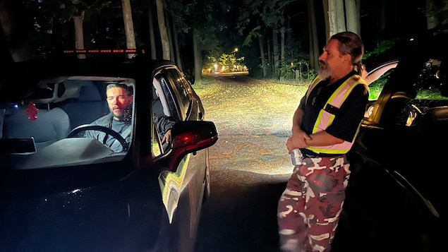 Deux hommes la nuit dans une zone boisée.