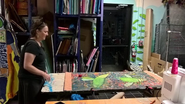 La fondatrice de Passion Works, Patty Mitchell, examine une banderole aux couleurs vives posée sur une table de son studio. La fondatrice de Passion Works, Patty Mitchell, examine une banderole aux couleurs vives posée sur une table de son studio.