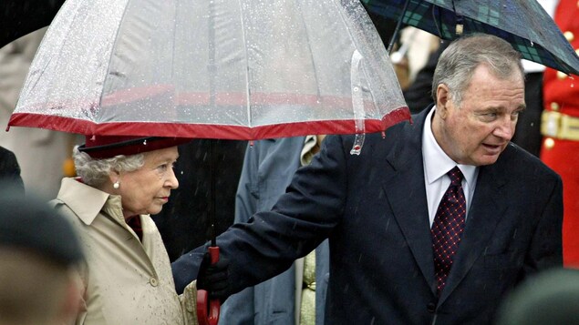 La reine tient un parapluie.