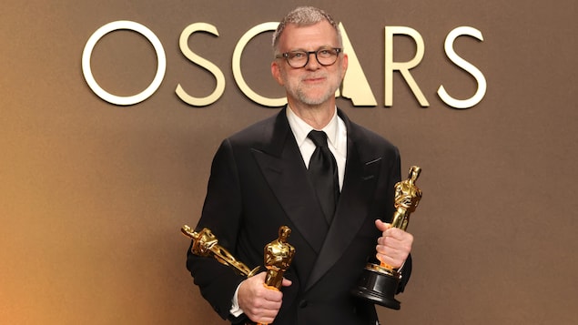Le cinéaste tient trois trophées dans ses mains aux Oscars.