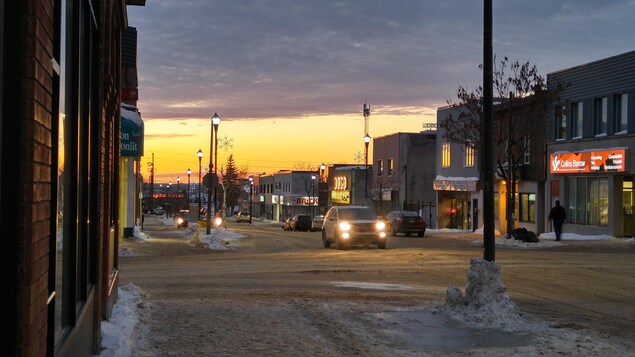 Le soleil se couche. Une voiture circule sur une rue commerciale. Le soleil se couche. Une voiture circule sur une rue commerciale.