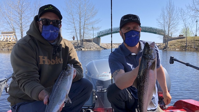 Deux pêcheurs montrent deux poissons.
