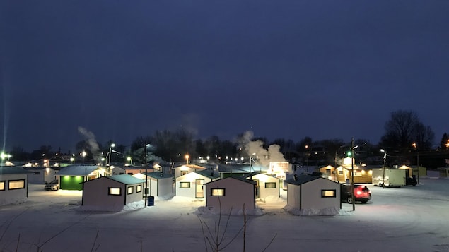 Des petites cabanes de pêcheurs blanches et vertes, avec de la fumée qui sort des cheminées, très tôt le matin