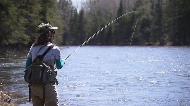 Une pêcheuse lance sa ligne à l'eau.