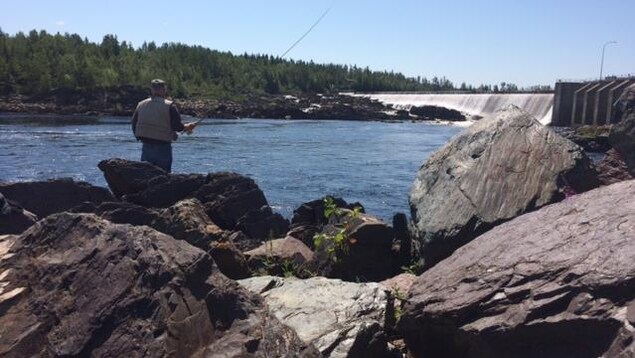 Un pêcheur de saumon lance sa ligne à l'eau dans une rivière. Un pêcheur de saumon lance sa ligne à l'eau dans une rivière.