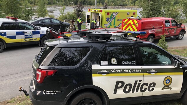 Des voitures de la Sûreté du Québec et des ambulances aux abords de la rivière Saint-François à Drummondville.
