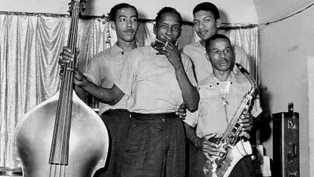 À droite, Robert « Pee Wee » Carter tenant son saxophone, accompagné de ses musiciens À droite, Robert « Pee Wee » Carter tenant son saxophone, accompagné de ses musiciens