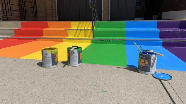Des sceaux de peinture devant des marches colorées.