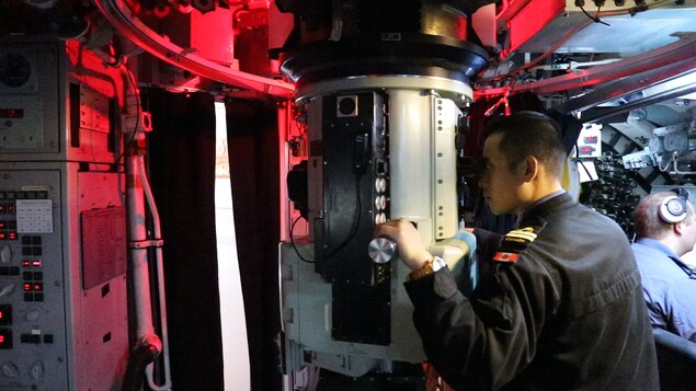 Dans la salle de contrôle, un sous-marinier regarde à travers le périscope Dans la salle de contrôle, un sous-marinier regarde à travers le périscope