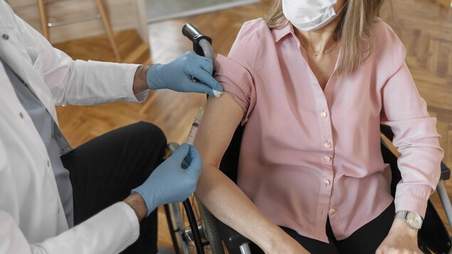 Une personne en chaise roulante reçoit un vaccin.