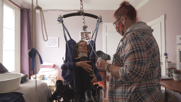 Nancy Leblond transfère Marie-Claude Lépine vers son lit au moyen d'un lève-personne.