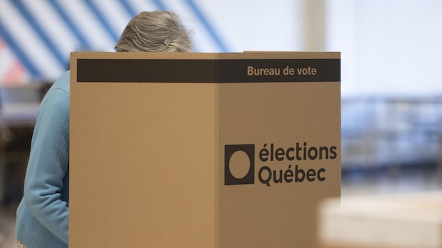 Une femme vote derrière un panneau dans un bureau de vote.