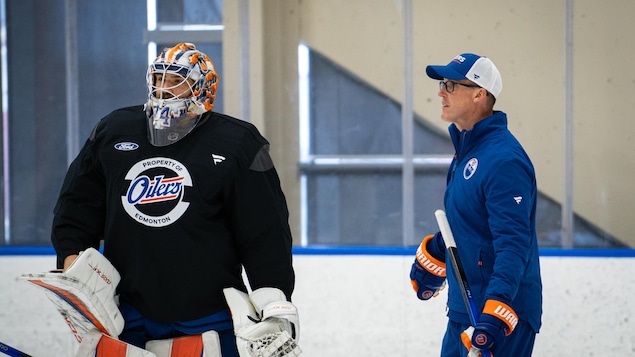 Un homme avec une casquette et un baton de hockey sur la glace.