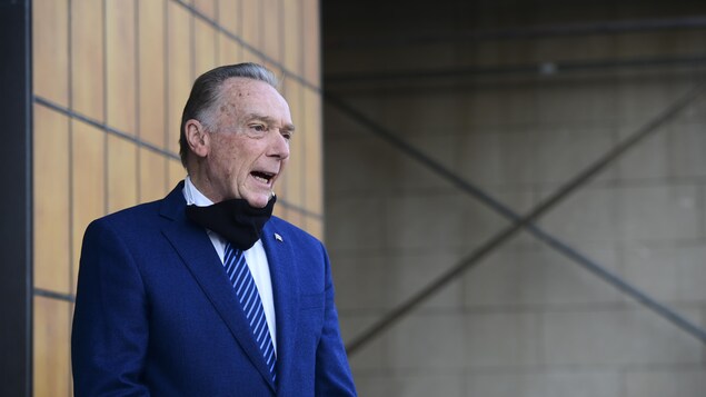 Peter Kent parle, un masque sous le menton.