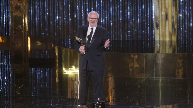 Un homme prononce un discours avec une statuette dans les mains. Un homme prononce un discours avec une statuette dans les mains.