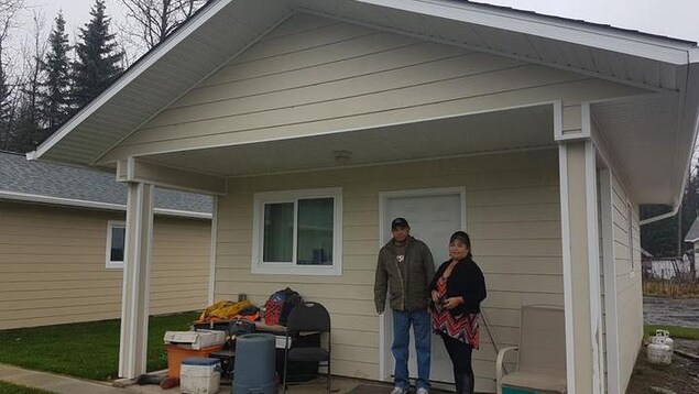 Un homme et une femme debout devant une petite maison