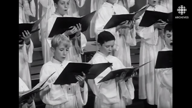 Petits Chanteurs du Mont-Royal qui chantent un chant de Noël en soutane avec leurs cahiers de chant