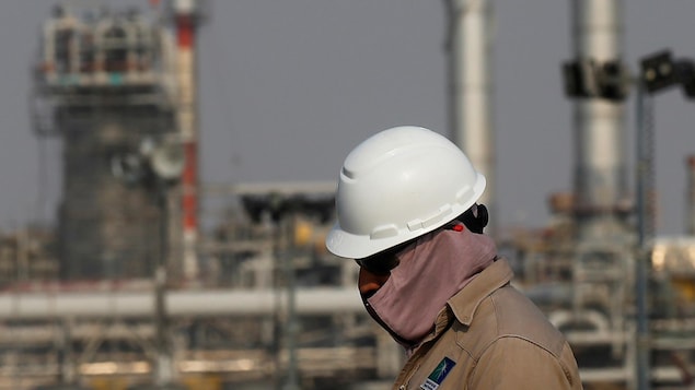 Un travailleur devant les installations d'un complexe pétrolier.