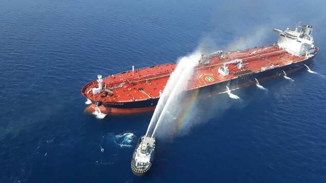 Des jets d'eau sont tirés d'un bateau-pompe en direction d'un pétrolier.