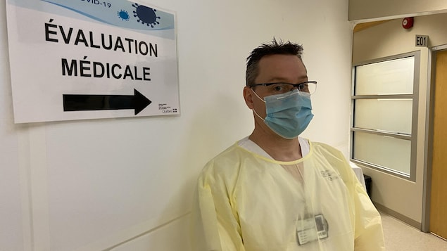 Un homme masqué placé devant un panneau indiquant « Évaluation médicale ».
