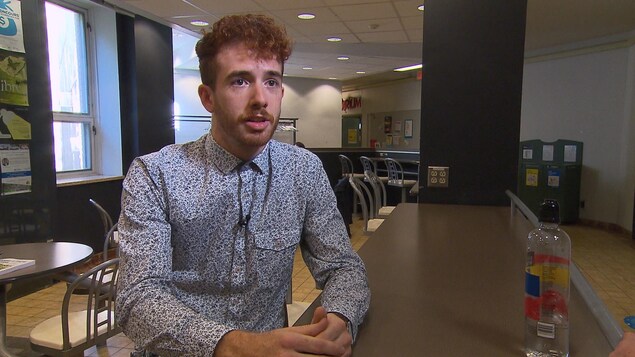 L'étudiant Philippe Verreault assis à une table. L'étudiant Philippe Verreault assis à une table.