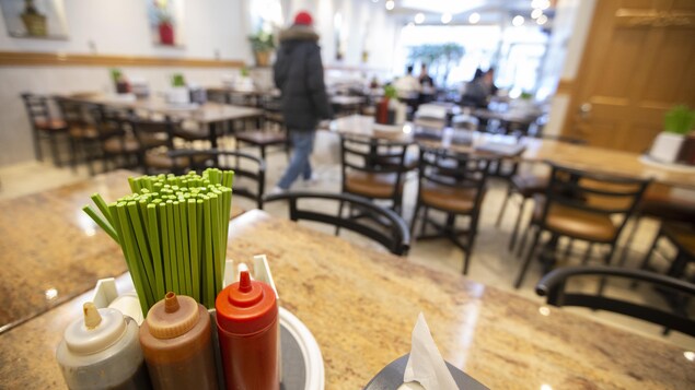 Des sauces et des baguettes sont posées sur une table, dans un restaurant pratiquement vide.