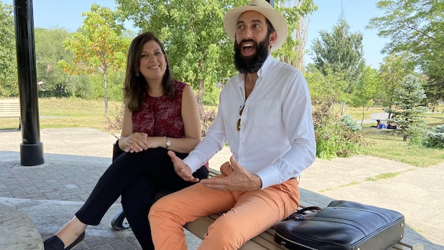 رجل ملتحٍ وامرأة جالسان على مقعد في متنزه في يوم مشمس.